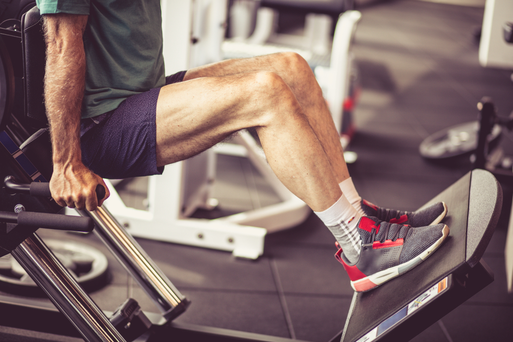 Senior man doing leg workouts at the gym