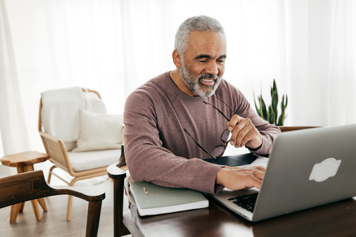 Older man smiling while using his laptop.