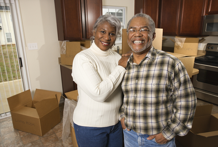 Senior African-American couple in kitchen with moving boxes.