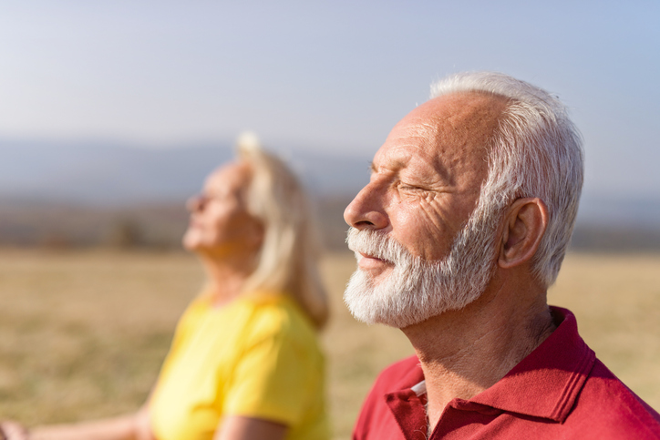 Senior man and senior woman meditating outdoors