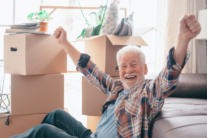 Senior man sitting on a couch next to moving boxes