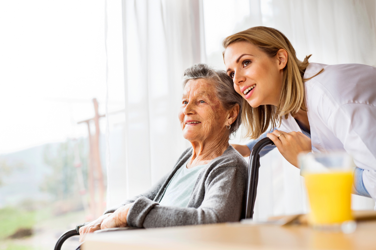 Caregiver talking to an elderly woman in a wheelchair.