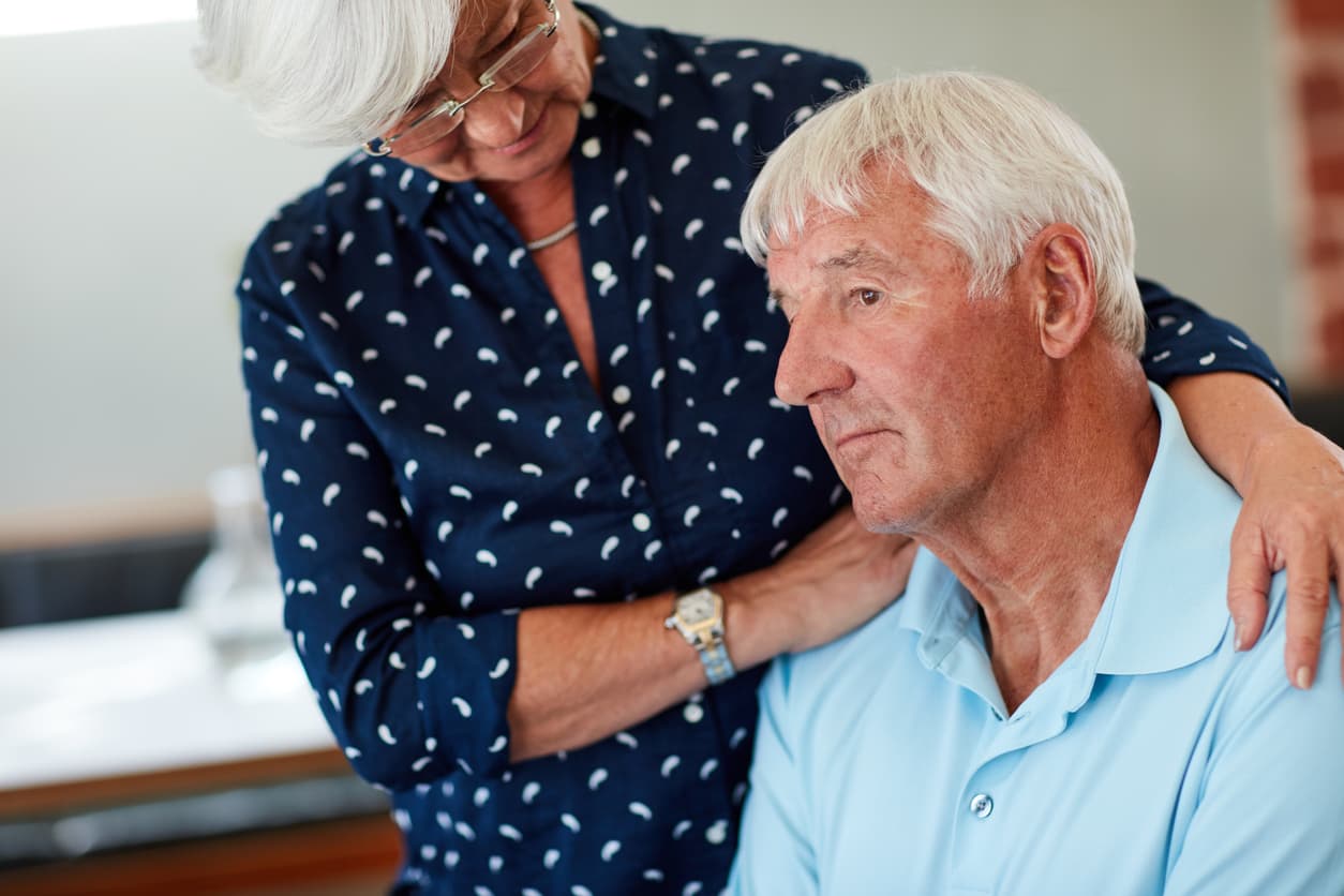 Older woman comforts her husband.